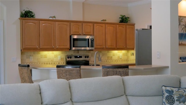 kitchen featuring stainless steel appliances, open floor plan, ornamental molding, tasteful backsplash, and light countertops