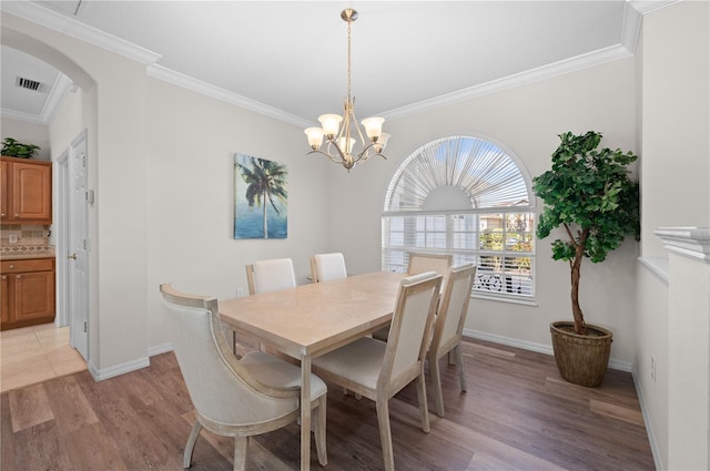 7424 Arrowhead Run, Lakewood Ranch, FL 34202 - dining room featuring arched walkways, ornamental molding, light wood finished floors, a chandelier, and baseboards