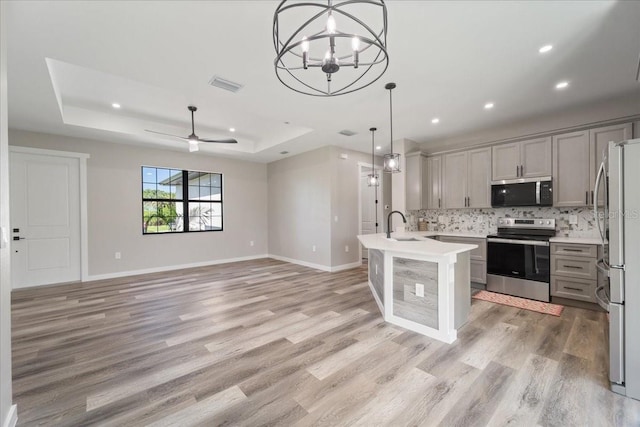 18274 Grace Ave, Port Charlotte, FL 33948 - kitchen with stainless steel appliances, a tray ceiling, gray cabinets, light wood finished floors, and recessed lighting