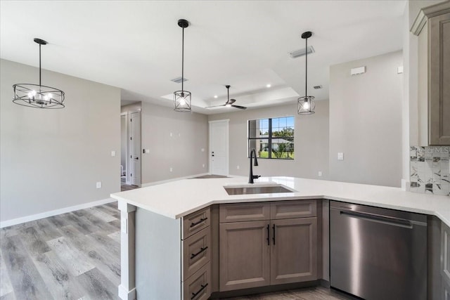 18274 Grace Ave, Port Charlotte, FL 33948 - kitchen featuring stainless steel dishwasher, a peninsula, light countertops, light wood-type flooring, and hanging light fixtures