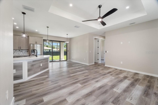 18274 Grace Ave, Port Charlotte, FL 33948 - unfurnished living room featuring a tray ceiling, light wood-style floors, recessed lighting, and a ceiling fan