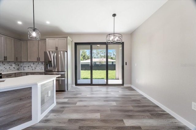 18274 Grace Ave, Port Charlotte, FL 33948 - kitchen featuring stainless steel refrigerator with ice dispenser, light countertops, a chandelier, decorative backsplash, and light wood-style flooring