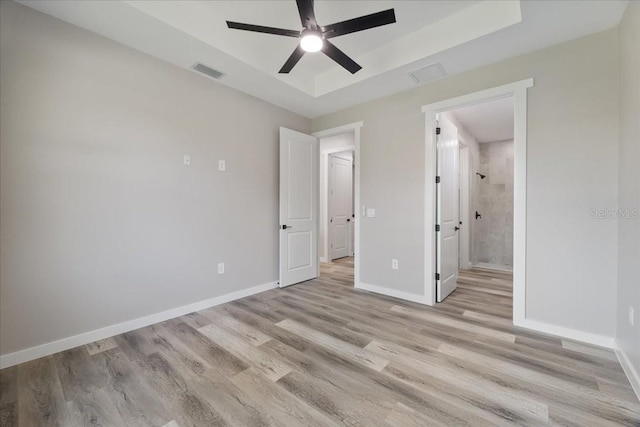 18274 Grace Ave, Port Charlotte, FL 33948 - unfurnished bedroom featuring light wood finished floors, a raised ceiling, ensuite bath, and a ceiling fan