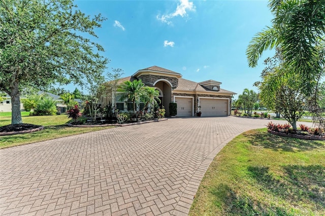mediterranean / spanish-style house featuring stone siding, a garage, decorative driveway, and a front lawn