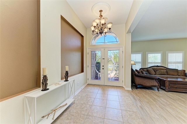foyer entrance with a chandelier, french doors, light tile patterned flooring, and baseboards