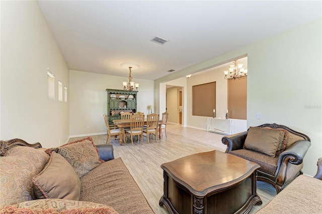 living area featuring a chandelier, light wood finished floors, and baseboards
