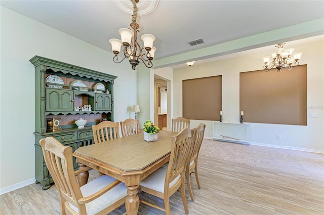 dining area with a chandelier, baseboards, and light wood-type flooring