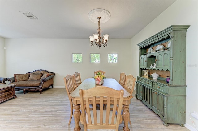 dining area with a chandelier, light wood finished floors, and baseboards