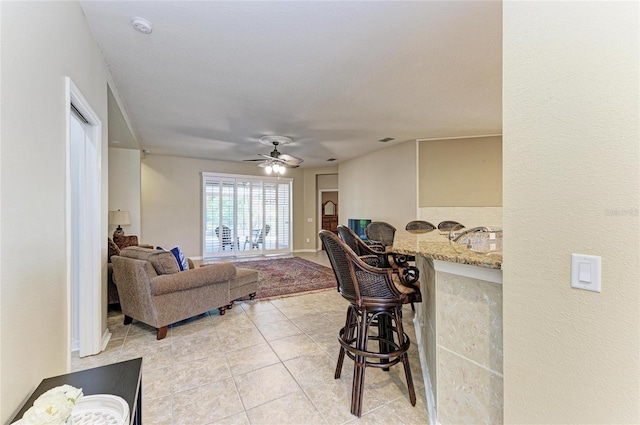 living area with light tile patterned floors and ceiling fan