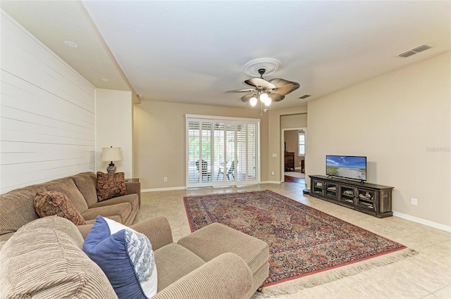 tiled living area with ceiling fan and baseboards