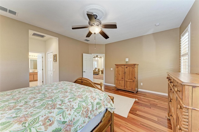 bedroom with light wood-type flooring, baseboards, ensuite bathroom, and ceiling fan