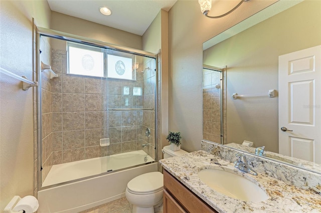 bathroom featuring toilet, combined bath / shower with glass door, vanity, and tile patterned floors