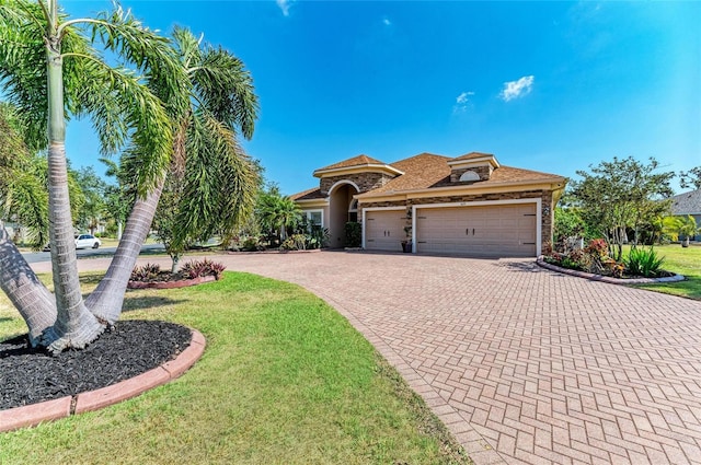 mediterranean / spanish-style home with an attached garage, a front yard, decorative driveway, and stucco siding