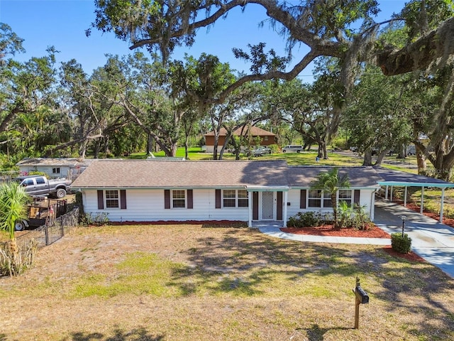 single story home with concrete driveway, a carport, a front lawn, and fence