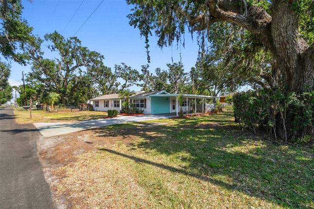 ranch-style home with concrete driveway, covered porch, a front yard, and a carport