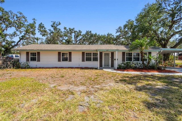 ranch-style house featuring an attached carport and a front lawn