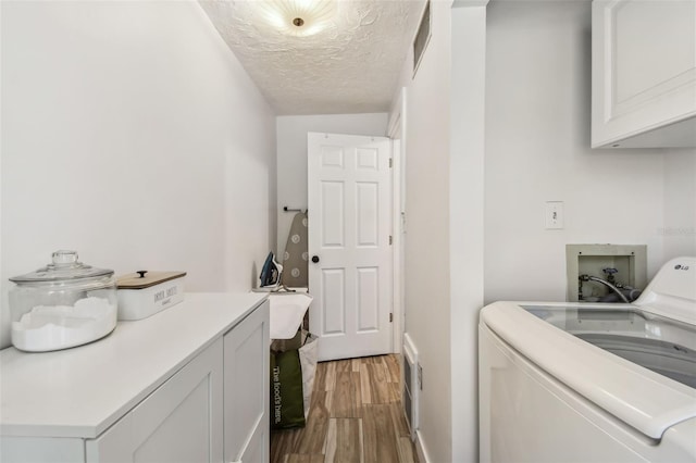 clothes washing area featuring cabinet space, separate washer and dryer, a textured ceiling, visible vents, and light wood-style floors
