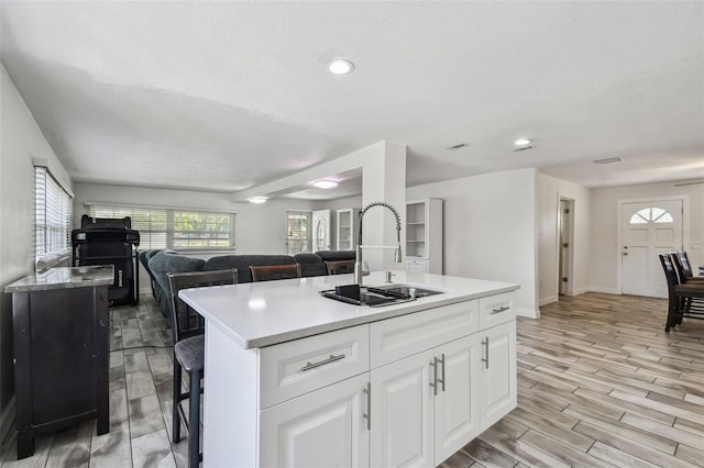 kitchen with a center island, a sink, open floor plan, white cabinets, and light wood-style floors