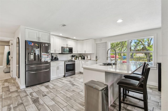 kitchen with stainless steel appliances, visible vents, a sink, light countertops, and white cabinets