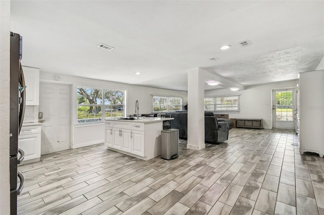 kitchen featuring a sink, open floor plan, visible vents, and white cabinets