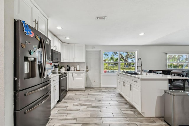 kitchen featuring a sink, black electric range, a healthy amount of sunlight, stainless steel fridge with ice dispenser, and visible vents