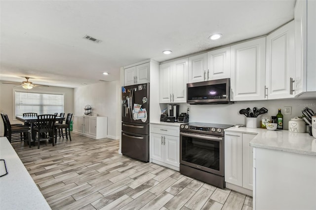 kitchen with appliances with stainless steel finishes, recessed lighting, a ceiling fan, white cabinets, and light wood-style floors