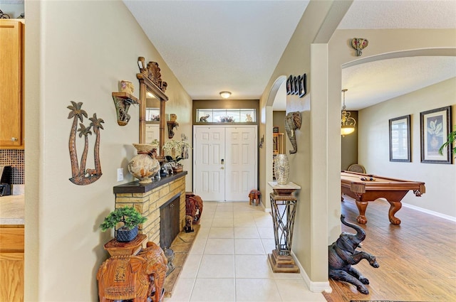 4211 30th Ln E, Bradenton, FL 34208 - foyer entrance featuring a fireplace, baseboards, arched walkways, billiards, and light tile patterned flooring