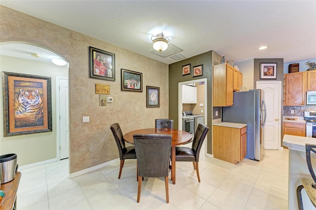 4211 30th Ln E, Bradenton, FL 34208 - dining space with washing machine and clothes dryer, a textured ceiling, visible vents, baseboards, and arched walkways