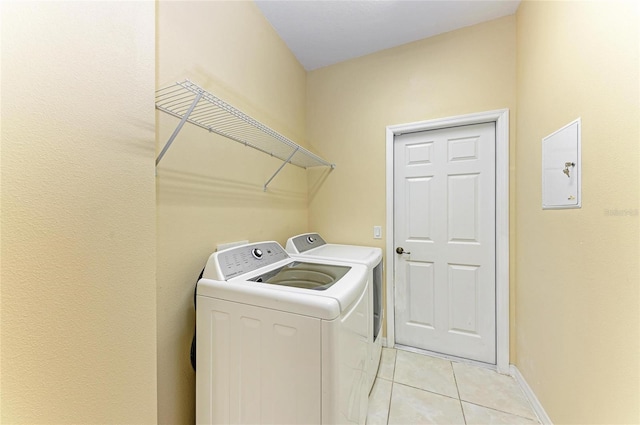 clothes washing area featuring independent washer and dryer, light tile patterned floors, and baseboards
