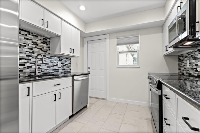 kitchen with a sink, stainless steel appliances, white cabinets, baseboards, and backsplash