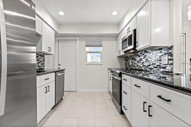 kitchen with dark stone counters, stainless steel appliances, white cabinetry, baseboards, and decorative backsplash