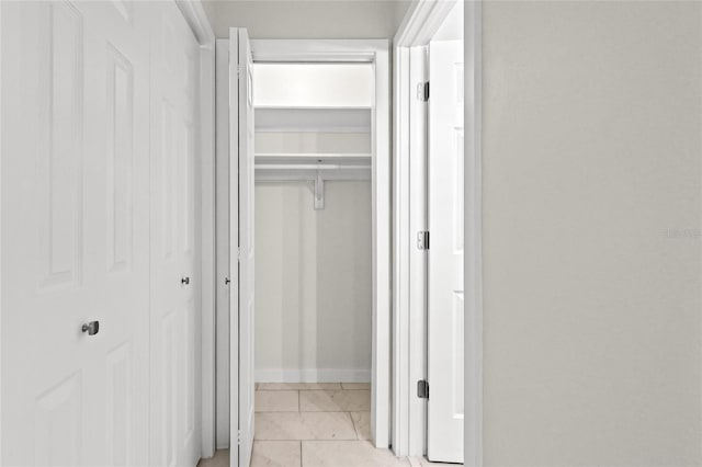 hallway with baseboards and light tile patterned floors