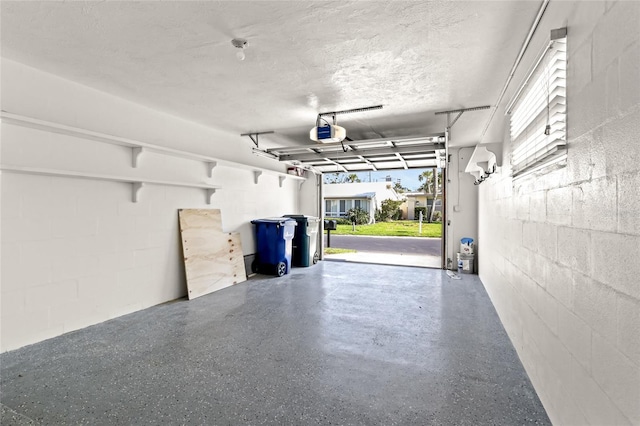 garage featuring concrete block wall and a garage door opener