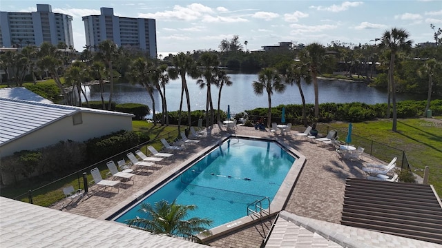community pool featuring a patio, a water view, and fence