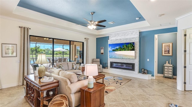 20359 Cristoforo Pl, Venice, FL 34293 - living room with a tray ceiling, ceiling fan, crown molding, a large fireplace, and baseboards