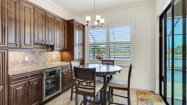 20359 Cristoforo Pl, Venice, FL 34293 - dining space featuring wine cooler, a chandelier, baseboards, crown molding, and a bar