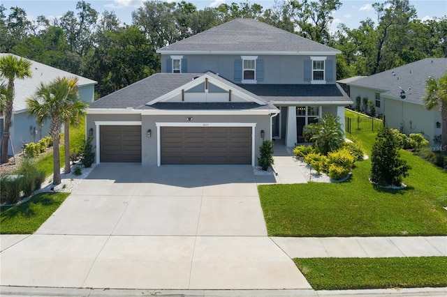 traditional home with concrete driveway, a garage, stucco siding, a front lawn, and a shingled roof
