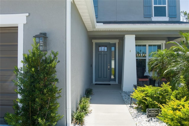 property entrance with a porch and stucco siding