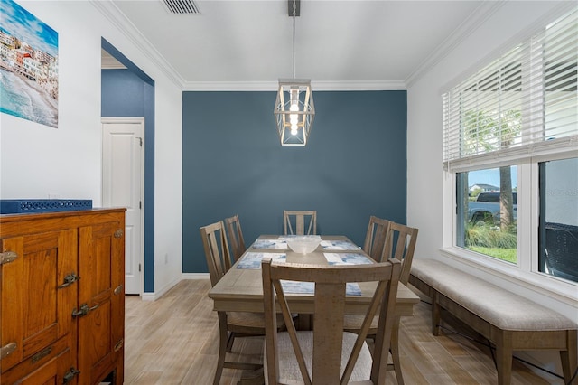 dining space with light wood finished floors, crown molding, and a healthy amount of sunlight