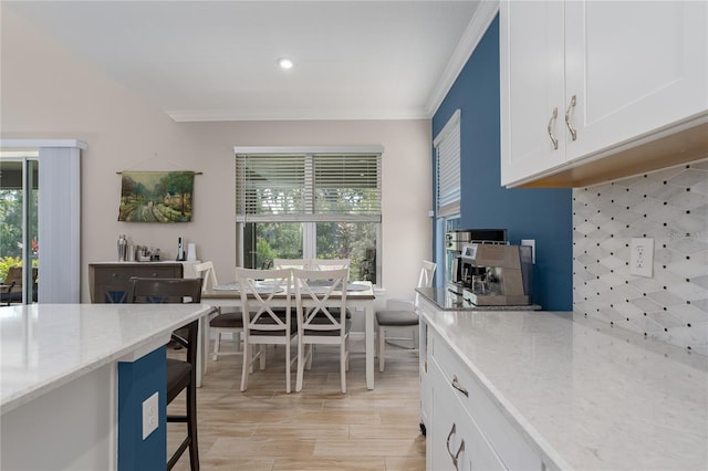 kitchen featuring white cabinetry, a wealth of natural light, light stone counters, and ornamental molding