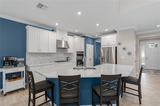 kitchen with a sink, under cabinet range hood, a breakfast bar area, and appliances with stainless steel finishes