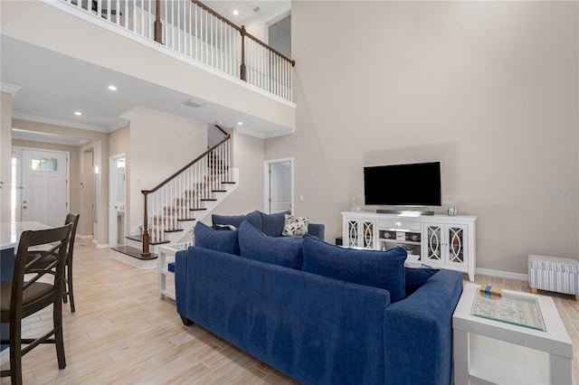 living room with baseboards, stairway, light wood finished floors, and crown molding