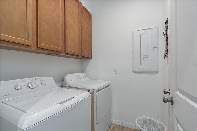 clothes washing area featuring electric panel, cabinet space, baseboards, and independent washer and dryer