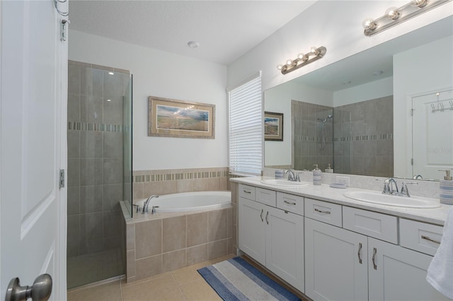 bathroom featuring walk in shower, a garden tub, tile patterned flooring, and a sink