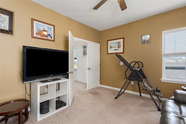 workout room with a ceiling fan, baseboards, and carpet floors