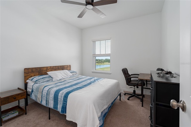 carpeted bedroom with a water view, baseboards, and a ceiling fan