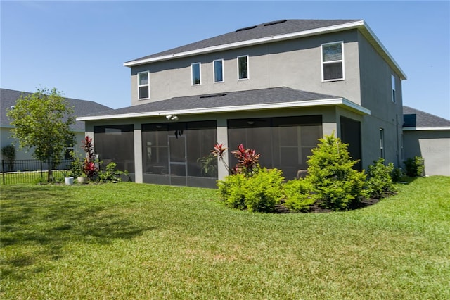 rear view of property with a yard, a sunroom, stucco siding, and fence