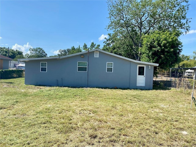 view of property exterior with a yard, stucco siding, and fence