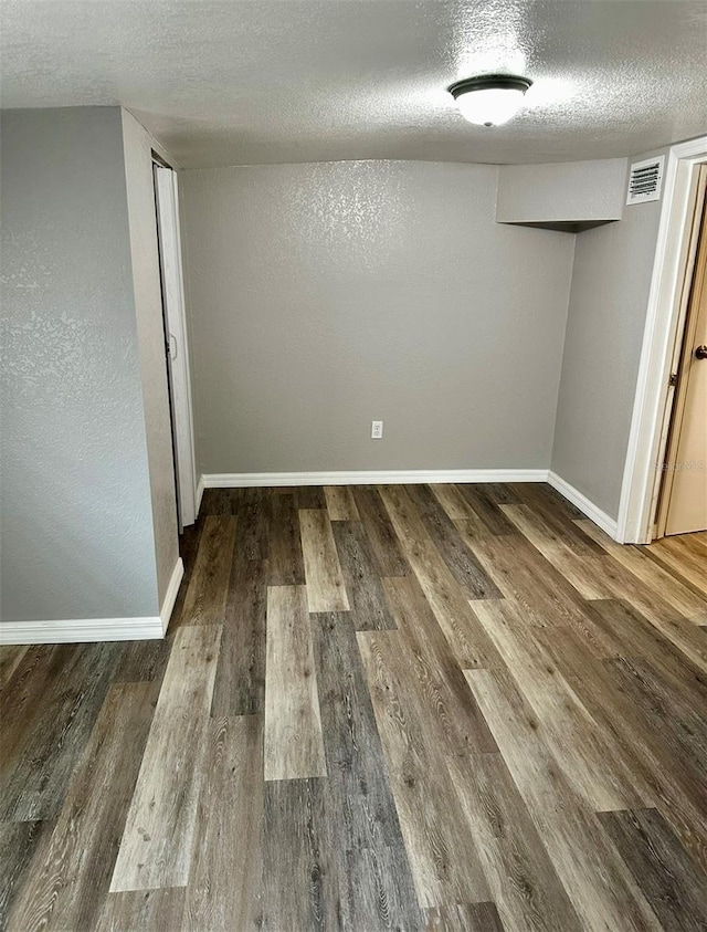 finished basement featuring a textured ceiling, baseboards, and visible vents
