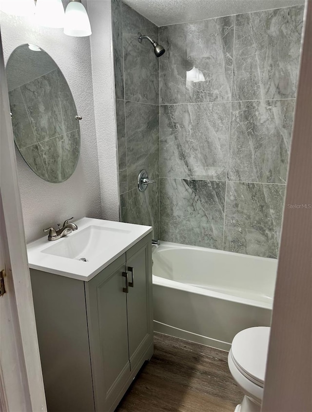 bathroom featuring a textured ceiling, toilet, vanity, wood finished floors, and bathing tub / shower combination